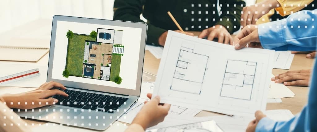 Architects and contractors review printed floor plans and a site plan on a laptop at a project coordination meeting.