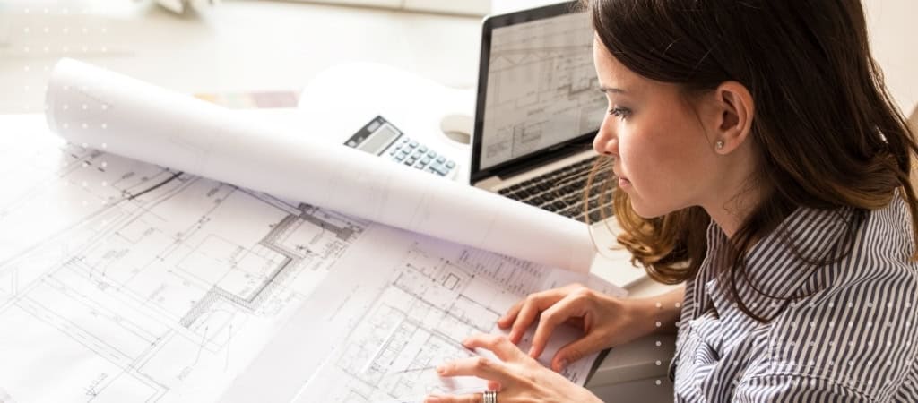Architect reviewing construction plans and contracts at desk.