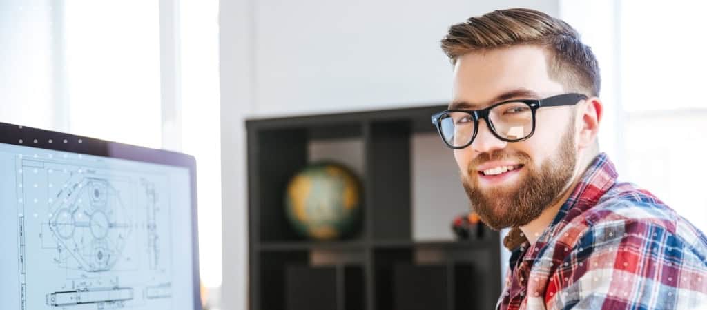 Young male architect working on contract plans at computer desk.