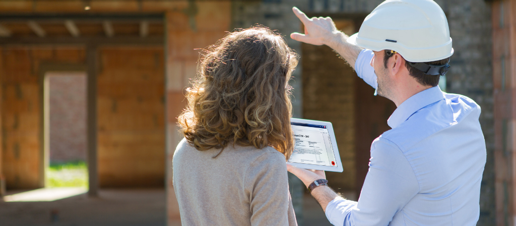 An architect reviewing the details of their contract with their client in front of the completed structure during final completion