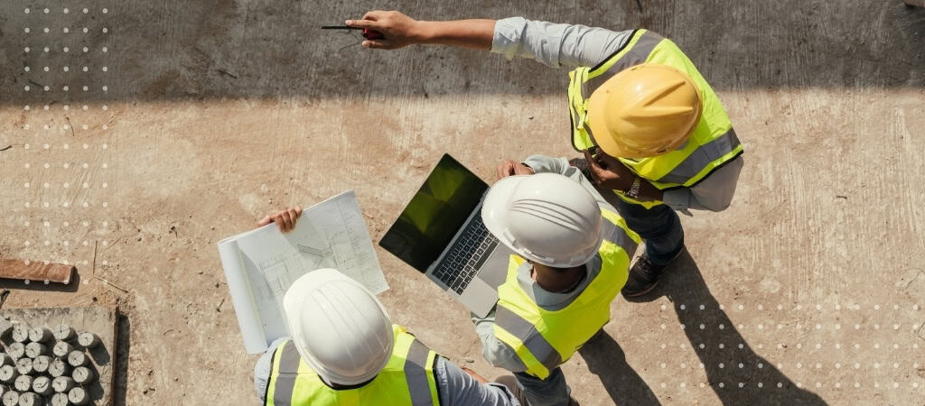 Construction team reviewing project plans and contracts on site.
