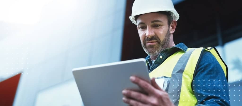 Construction site manager reviewing digital plans on a tablet.