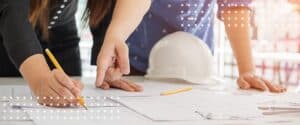 Team members reviewing construction plans with safety helmet on table.