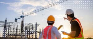 Engineers discussing construction plans at a building site with crane in background.