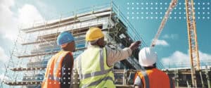 Construction workers in hard hats looking up at a scaffolded building on a jobsite where preliminary notice rules apply.
